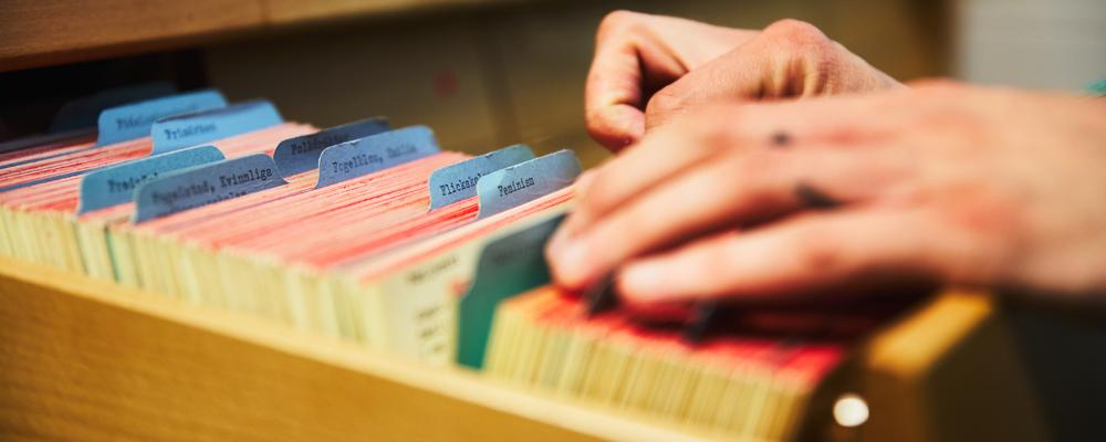 Händer som bläddrar i kortkatalog