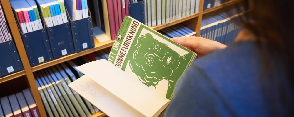 Person läser tidskrifter i KvinnSams tidskriftshylla