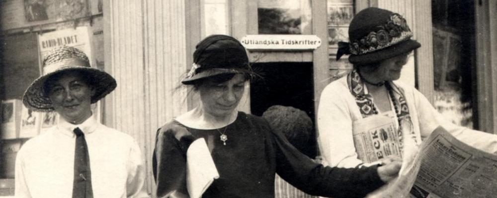 Eva Andén, Elin Wägner och okänd kvinna läser Tidevarvet framför en tidninskiosk
