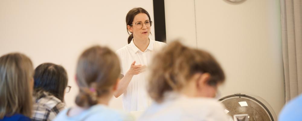 Person pratar inför grupp vid ett bord